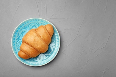 Photo of Plate with tasty croissant on gray background, top view