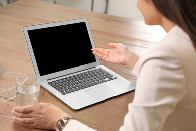 Woman using video chat on laptop in home office, closeup. Space for text