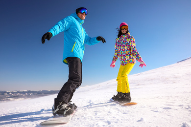 Photo of Couple snowboarding on snowy hill. Winter vacation