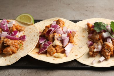 Delicious tacos with vegetables and meat on grey textured table, closeup