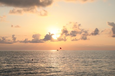 Photo of Picturesque view of beautiful sea and people parasailing at sunset