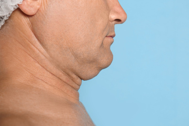 Photo of Mature man with double chin on blue background, closeup. Space for text