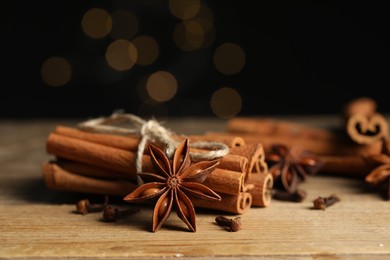 Photo of Bunch of cinnamon sticks, anise star and dry clove buds on wooden table, closeup