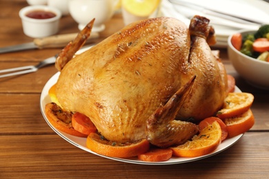 Photo of Delicious chicken with oranges on wooden table, closeup