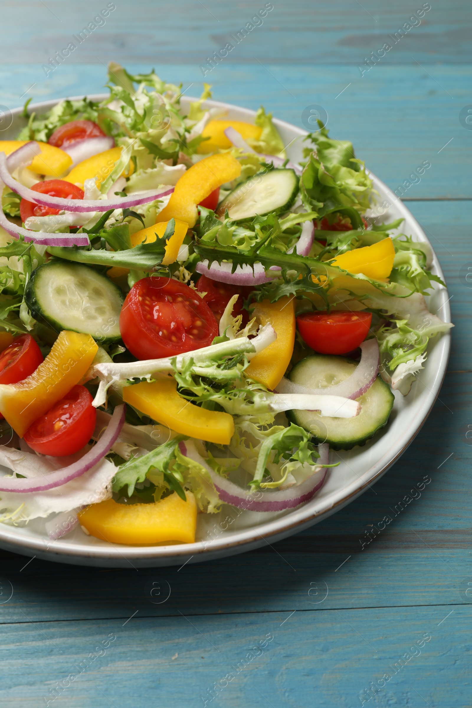 Photo of Tasty fresh vegetarian salad on light blue wooden table, closeup