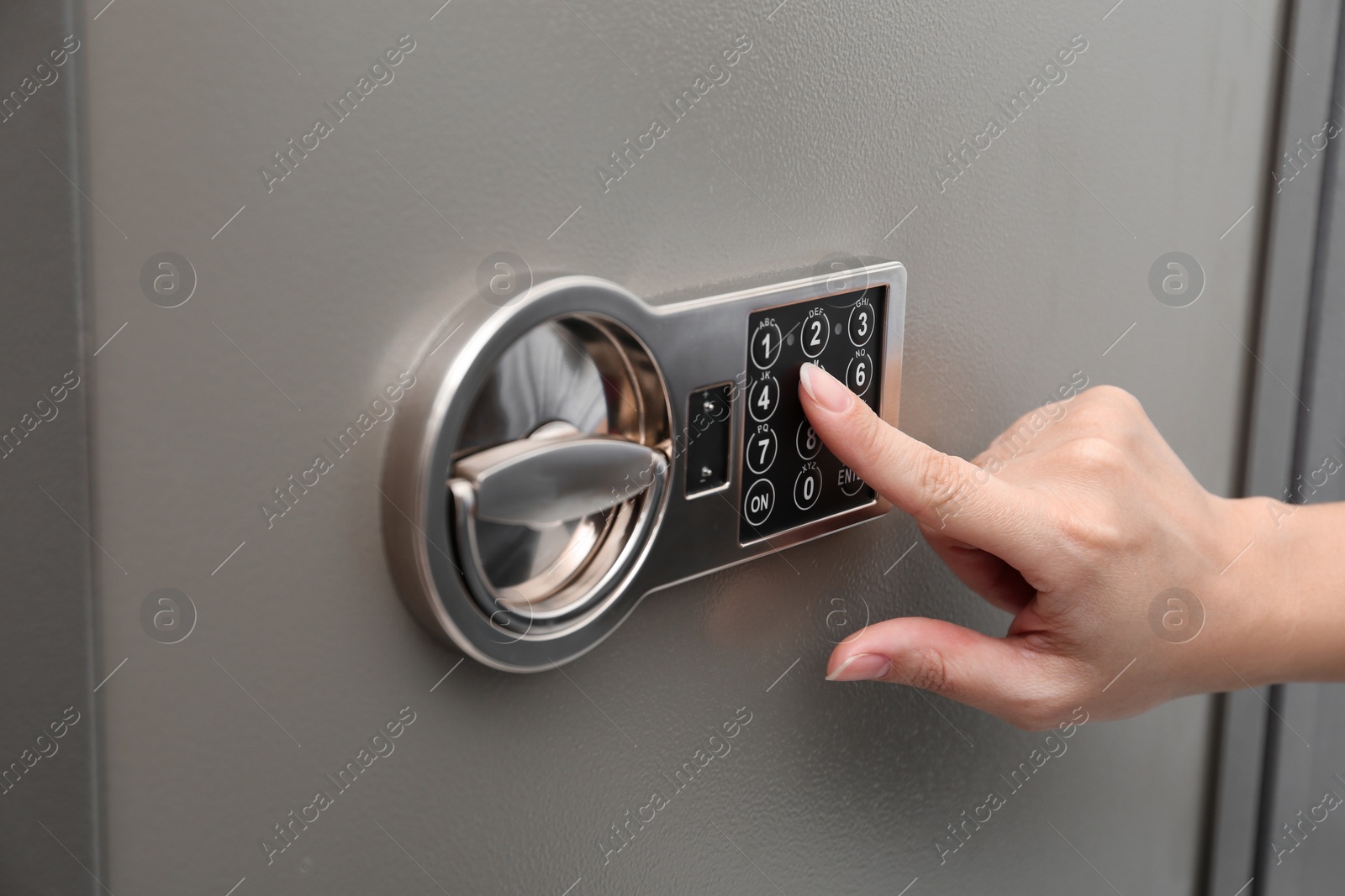 Photo of Woman entering code on keypad of modern safe, closeup