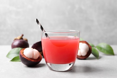 Delicious fresh mangosteen juice in glass on light grey table