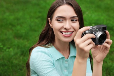 Photo of Young woman with camera taking photo outdoors. Interesting hobby