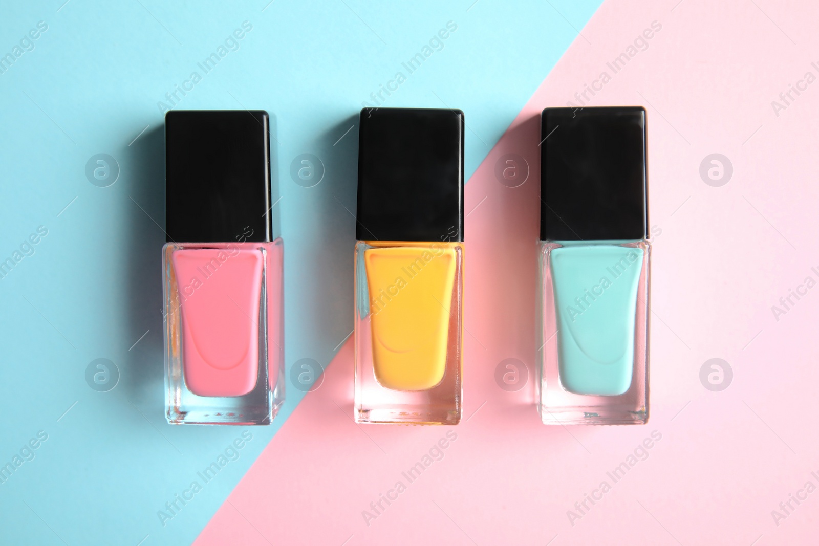 Photo of Bottles of nail polish on color background, top view