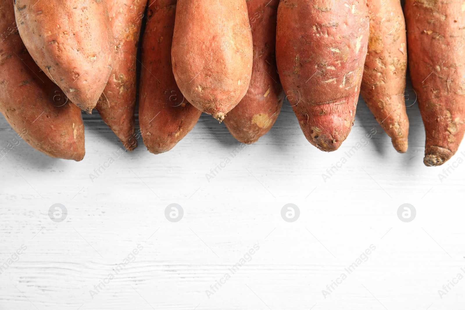 Photo of Flat lay composition with sweet potatoes and space for text on white wooden background