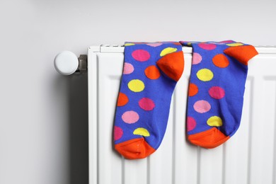 White radiator with colorful socks on light wall