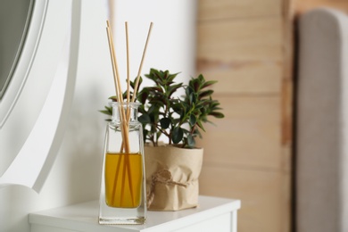 Photo of Aromatic reed air freshener on dressing table in room. Space for text