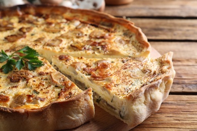Photo of Delicious pie with mushrooms and cheese on brown wooden table, closeup