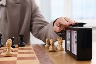 Photo of Man turning on chess clock during tournament at table, closeup