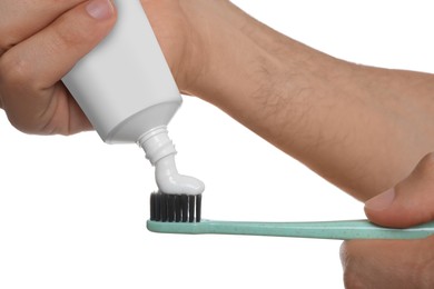 Man applying toothpaste on brush against white background, closeup