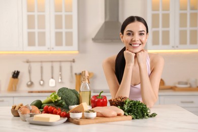 Photo of Happy woman with different products in kitchen. Keto diet