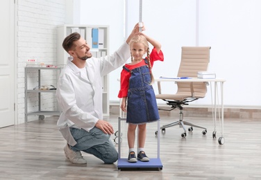 Doctor measuring little girl's height in hospital