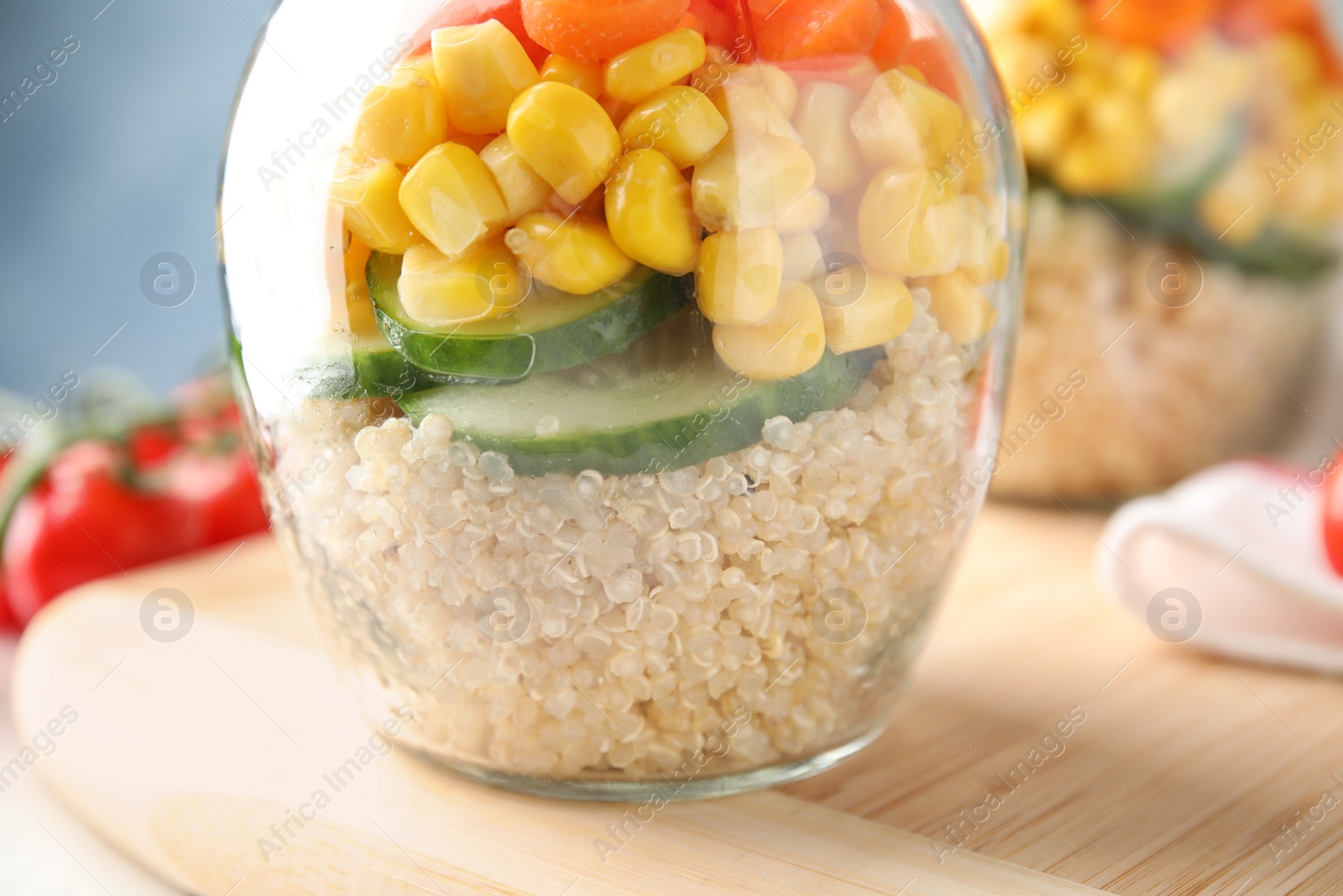 Photo of Jar with healthy quinoa salad and vegetables on board, closeup