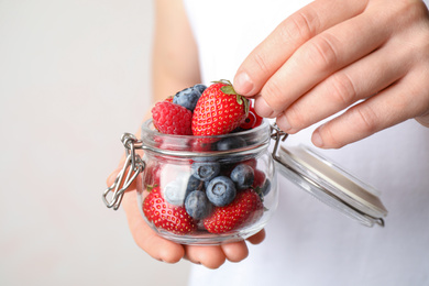 Woman with jar of delicious summer berries, closeup