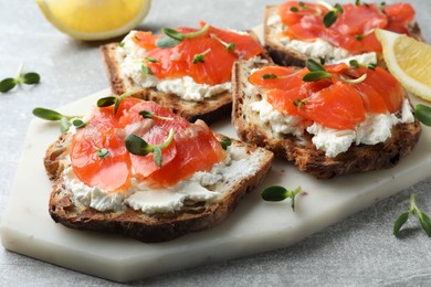 Photo of Delicious sandwiches with cream cheese, salmon and microgreens on light grey table, closeup
