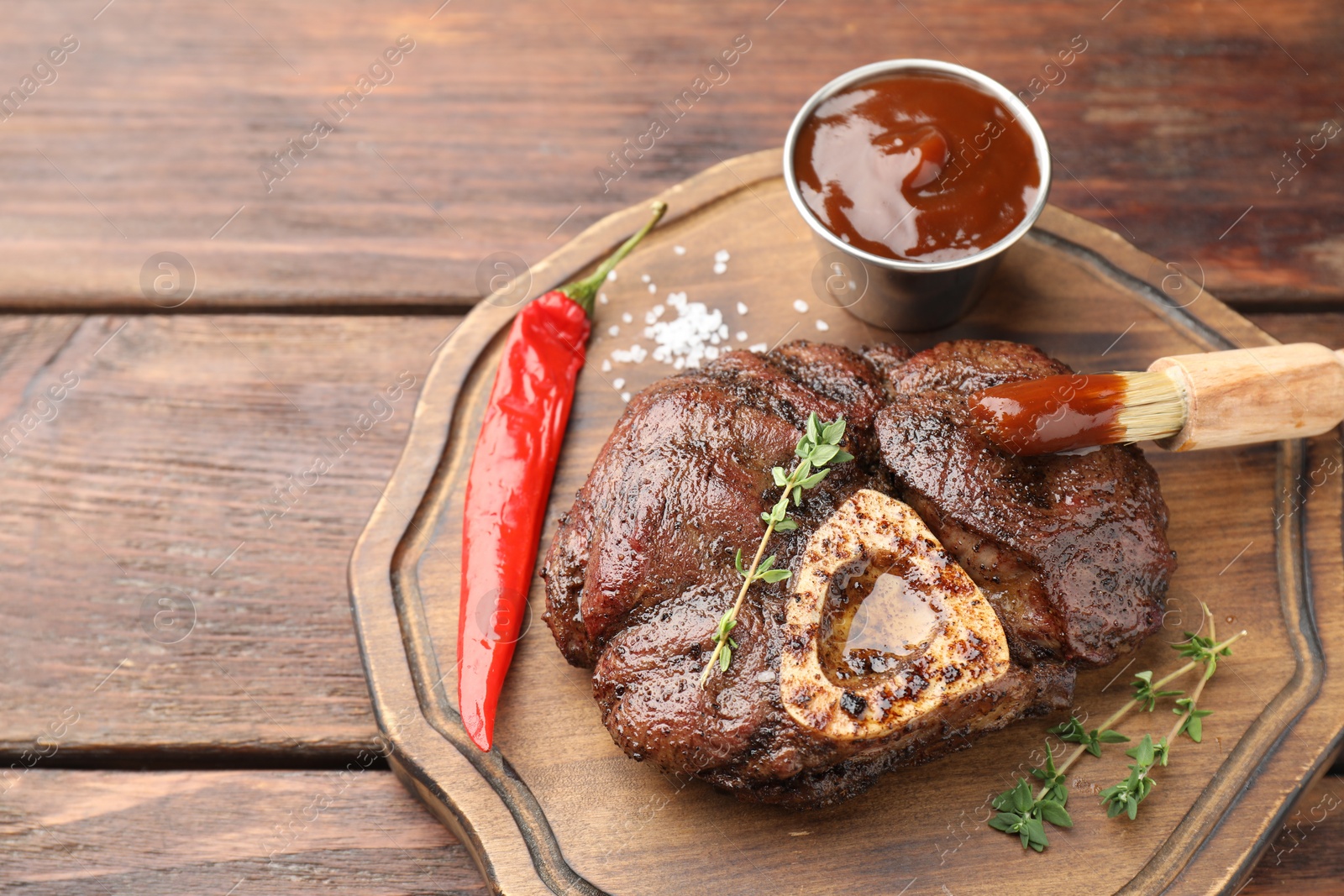 Photo of Delicious roasted beef meat served with sauce and spices on wooden table. Space for text