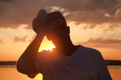 Photo of Man with cold pack suffering from heat stroke outdoors at sunset