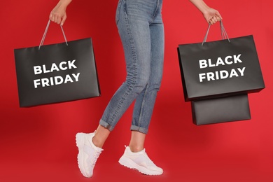 Photo of Woman with shopping bags on red background, closeup. Black Friday