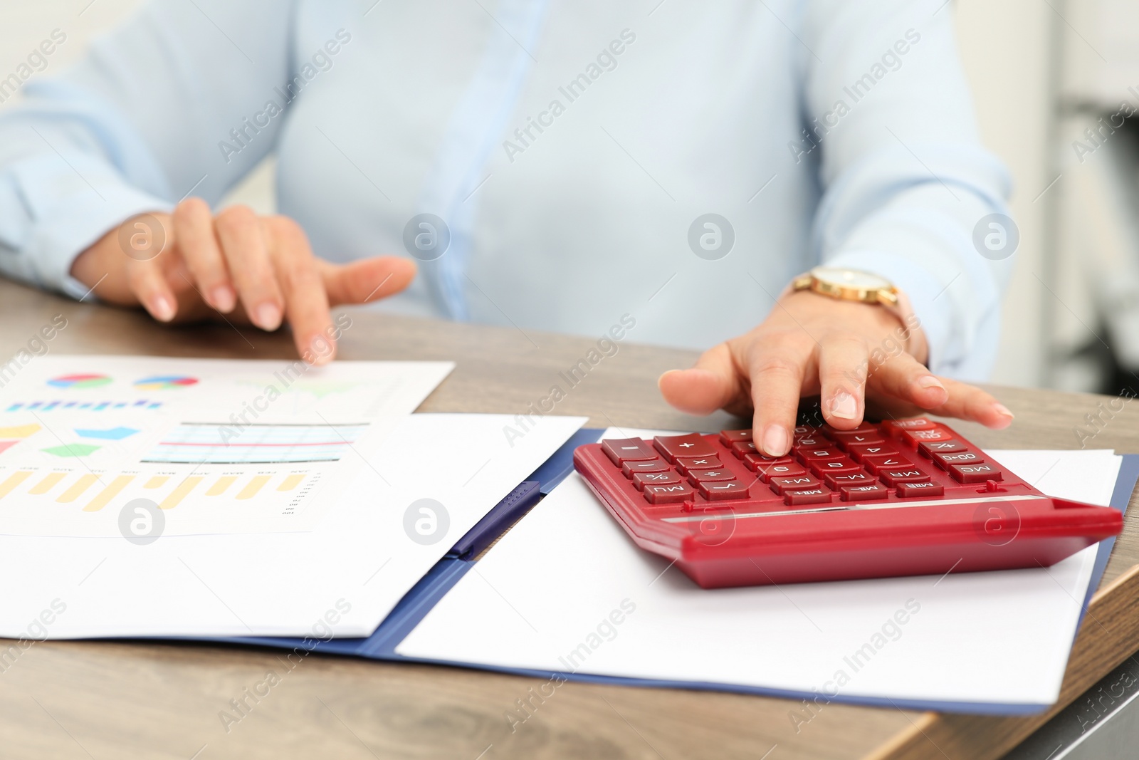 Photo of Accountant using calculator at wooden desk in office, closeup