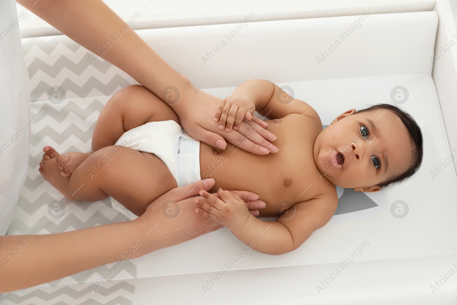 Photo of Mother and her cute child on changing table, above view. Baby massage and exercises