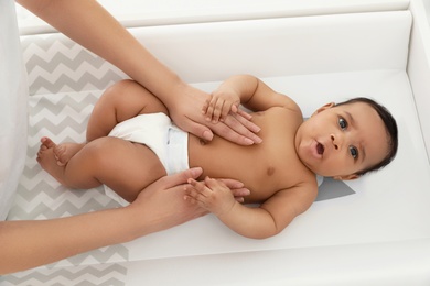 Mother and her cute child on changing table, above view. Baby massage and exercises