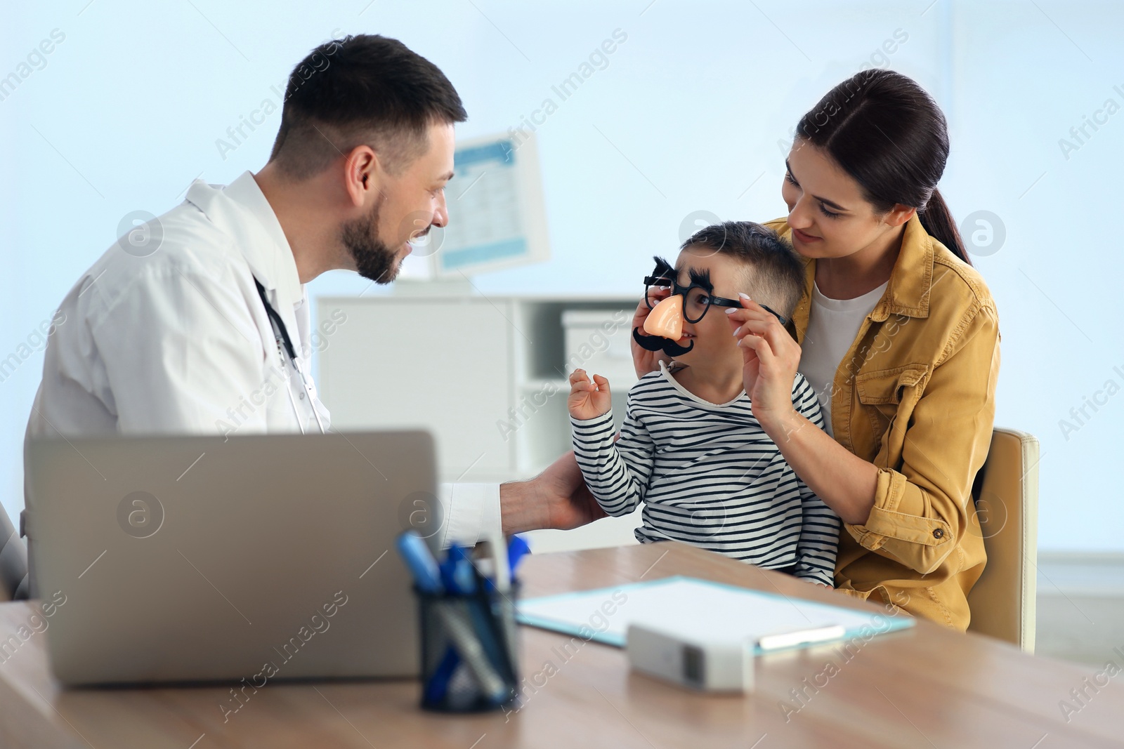 Photo of Mother and son visiting pediatrician in hospital. Doctor playing with little boy