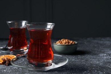 Photo of Glasses of traditional Turkish tea and ingredients on grey textured table, closeup. Space for text