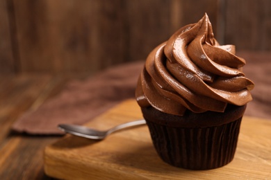 Delicious chocolate cupcake with cream on wooden table, closeup