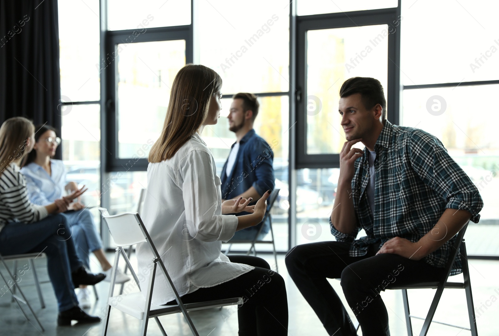 Photo of Psychotherapist working with patient in group therapy session indoors