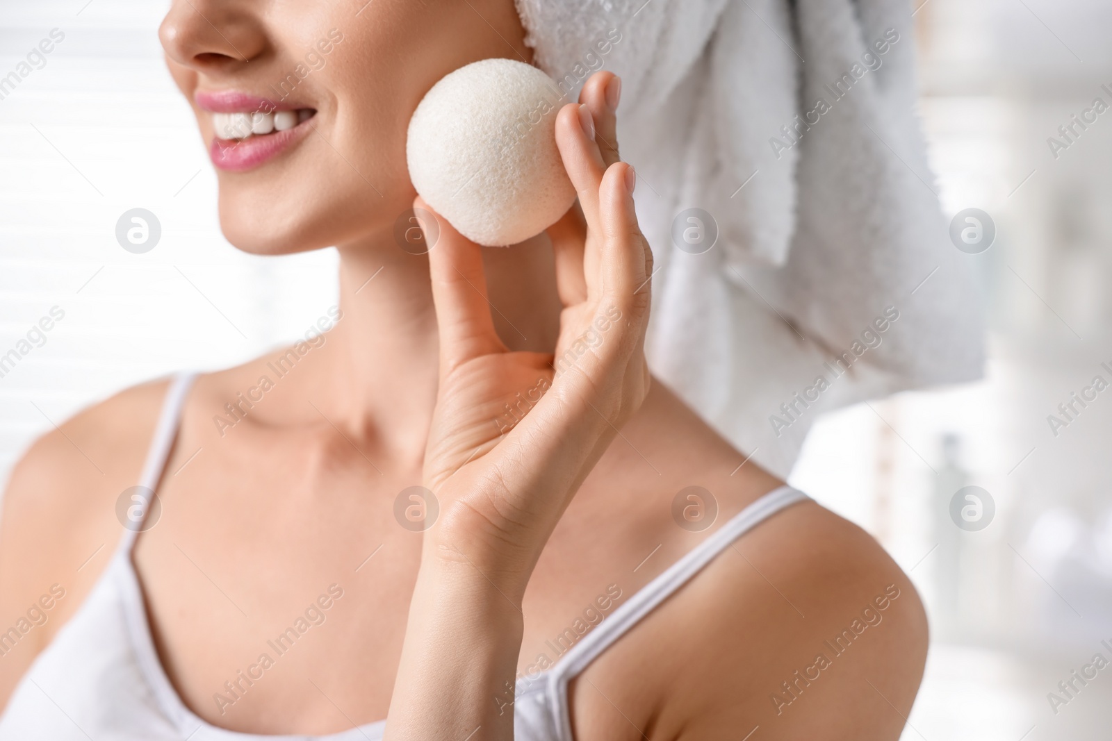 Photo of Happy young woman washing her face with sponge in bathroom, closeup