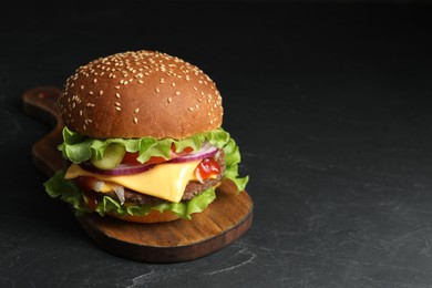 Photo of Delicious burger with beef patty and lettuce on dark table, space for text