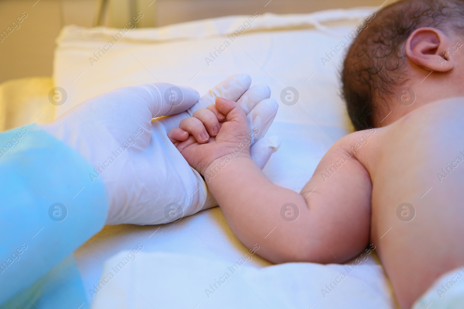 Photo of Doctor holding newborn child's hand in hospital, closeup