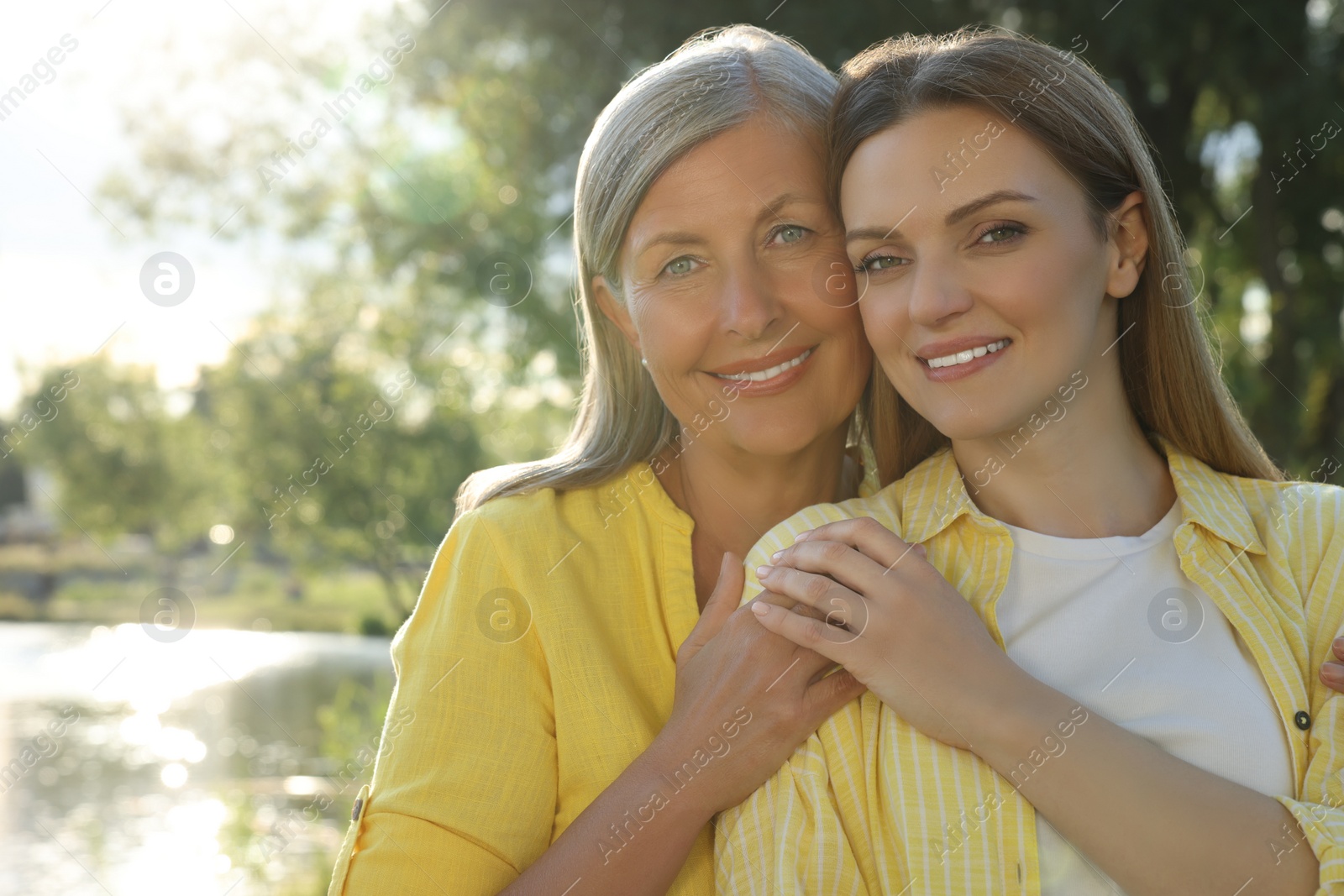 Photo of Family portrait of happy mother and daughter spending time together in park on sunny day. Space for text