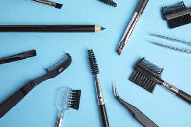 Set of professional eyebrow tools on blue background, flat lay