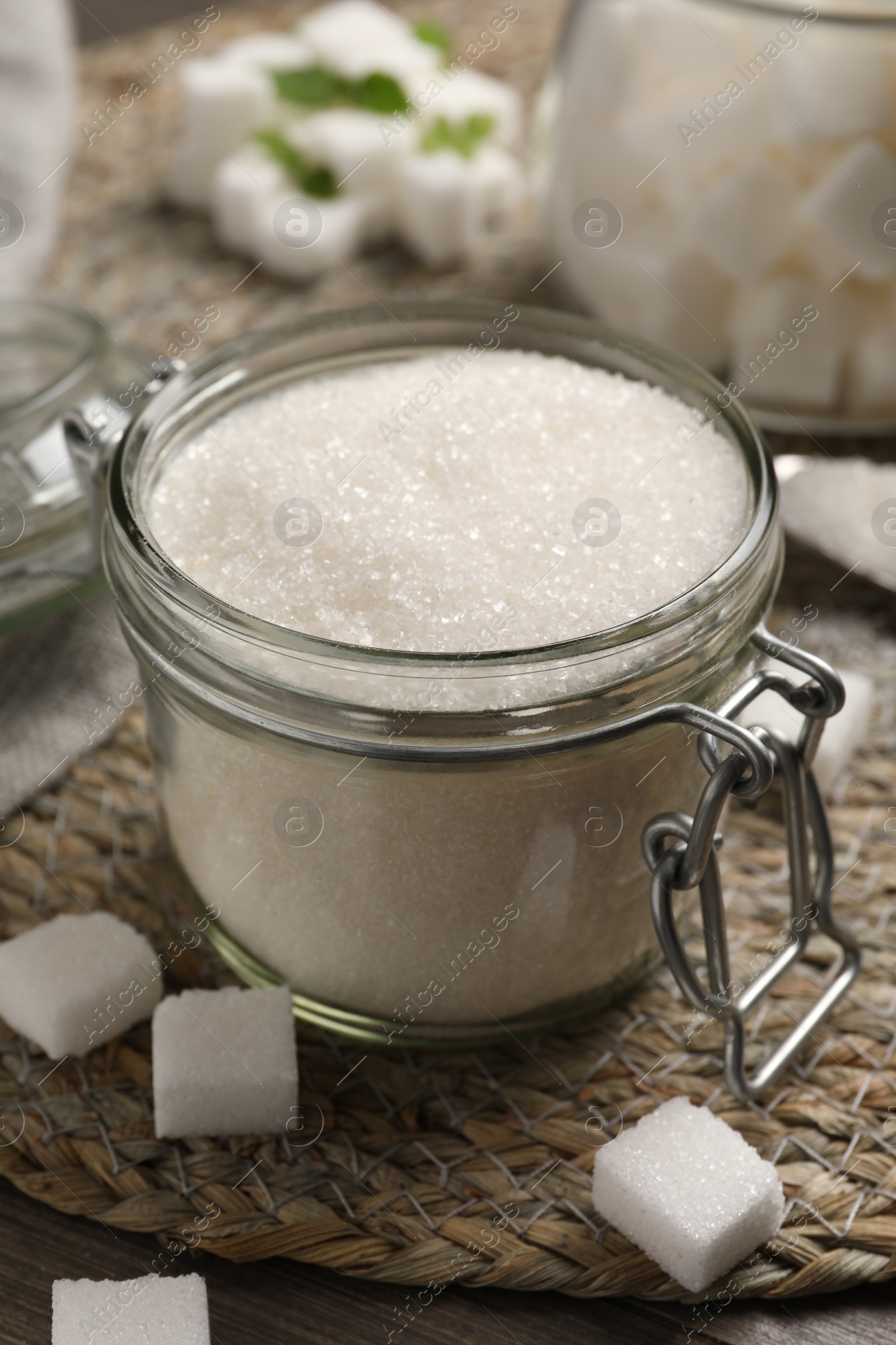 Photo of Jar of white sugar on wicker mat, closeup