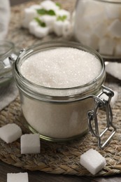 Jar of white sugar on wicker mat, closeup