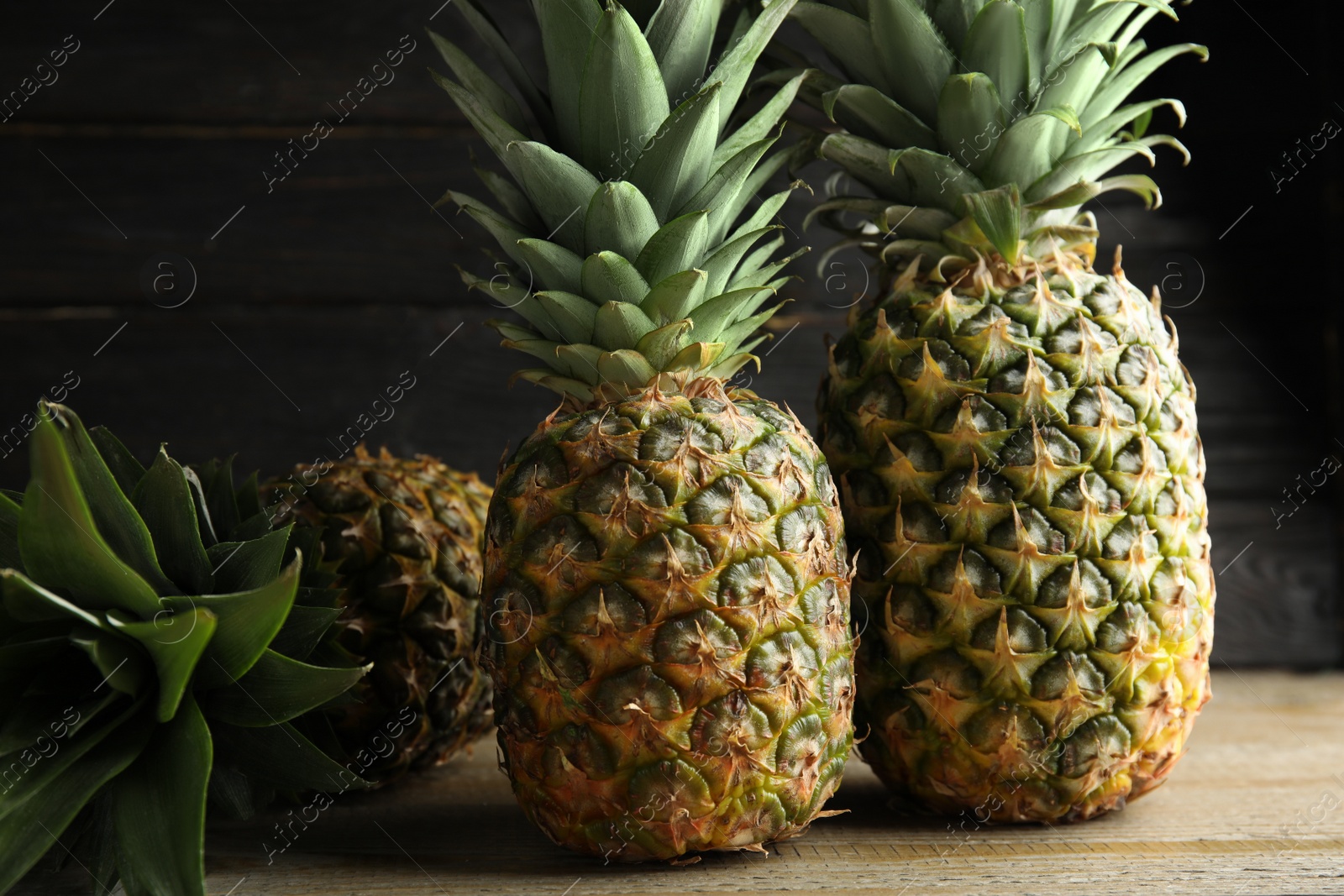 Photo of Fresh ripe juicy pineapples on wooden table