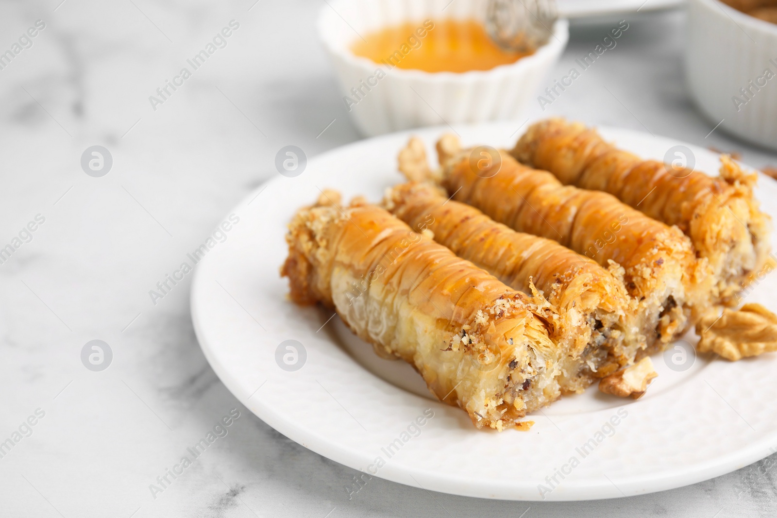 Photo of Eastern sweets. Pieces of tasty baklava on white marble table, closeup. Space for text