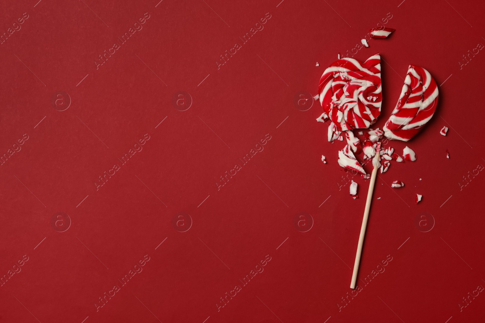 Photo of Broken heart shaped lollipop on red background, top view with space for text. Relationship problems concept