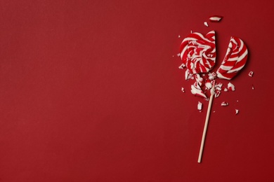 Photo of Broken heart shaped lollipop on red background, top view with space for text. Relationship problems concept