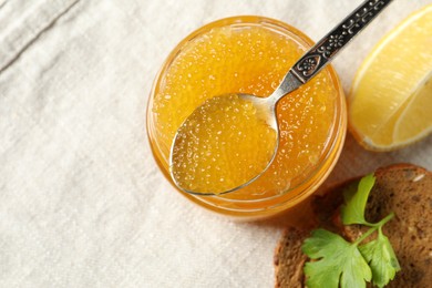 Photo of Fresh pike caviar in glass jar, bread, parsley and lemon on table, flat lay. Space for text