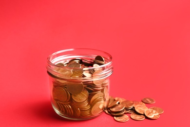 Glass jar and coins on color background. Space for text