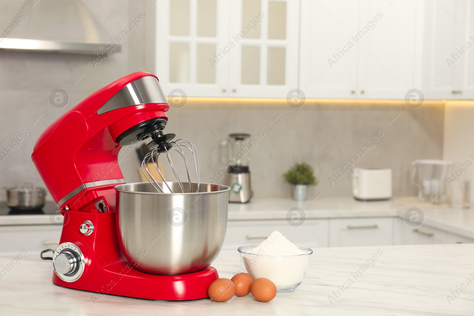 Photo of Modern red stand mixer, eggs and bowl with flour on white marble table in kitchen, space for text