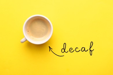 Photo of Word Decaf and cup of coffee on yellow background, top view