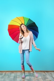 Photo of Woman with rainbow umbrella near color wall